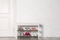 Shoe storage bench with different sneakers near brick wall