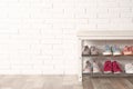 Shoe storage bench with different sneakers near brick wall