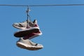 Shoe throwing tradition old shoes hanging on wires. Sneakers hanging on electric wires against a background of blue sky Royalty Free Stock Photo