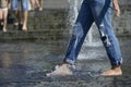Shoeless girl feet playing with fountain water jets at the square Royalty Free Stock Photo