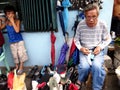 A shoemaker repairs a shoe for a customer along a street in Antipolo City, Philippines