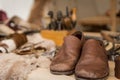 Shoemaker working desk with focus on ready shoes foreground and set of tools, material background, selective focus Royalty Free Stock Photo