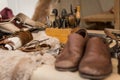 Shoemaker working desk with set of tools, ready shoes foreground and material background, selective focus Royalty Free Stock Photo