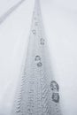 Shoeprints and tire print in snow Royalty Free Stock Photo