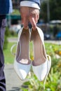 Shoes of the bride in the hands of the groom