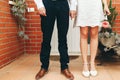 Shoes of groom and bride and her small wedding bouquet of pink roses with clasped hands after the ceremony. Wedding concept. Royalty Free Stock Photo