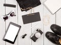 shoes, jeans, tablet pc, camera, notepad, sunglasses and essentials on white wooden desk