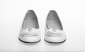 Shoes made out of white leather on white background, isolated. Footwear for women on flat sole with pearl bead as decor
