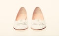 Shoes made out of white leather on white background, isolated. Footwear for women on flat sole with pearl bead as decor