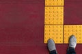 Shoes on yellow dot tactile paving for blind handicap on tiles pathway in japan, walkway for blindness people Royalty Free Stock Photo