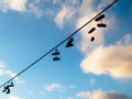 Shoes silhouette hanging on a cable with blue sky background