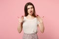 Shoked irritated young woman in casual light clothes posing isolated on pink background, studio portrait. People