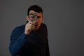 Shoked man with magnifying glass on grey background. Curious young man with magnifying glass Isolated on grey background