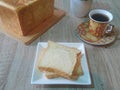 Shokupan or Japanese Milk Bread on the white ceramic plate with a cup of tea on the wooden table