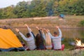 Shoot from back. A group of happy friends camping at riverside, dancing hold hands up  and enjoy view. Holidays fun Royalty Free Stock Photo