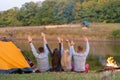 Shoot from back. A group of happy friends camping at riverside, dancing hold hands up  and enjoy view. Holidays fun Royalty Free Stock Photo