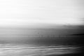 A shoot of dusk at a lake, with with a bird flying and many diagonal lines created by clouds and water waves