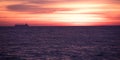 Shoot of perfect orange-red sunset beyond the clouds near dark sea waves. Royalty Free Stock Photo