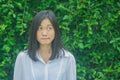 Shoot photo Asian woman portrait wear white shirt, thinking and looking sideways with green tree background.