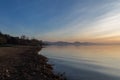 A shoot of a sunset over a lake, with beautiful warm colors and many diagonal lines created by clouds and water waves