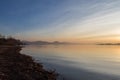 A shoot of a sunset over a lake, with beautiful warm colors and many diagonal lines created by clouds and water waves