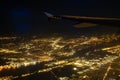 Shooting from the air. The plane in the sky flies over the night city. Golden lights. Dark blue sky. Beautiful city landscape.