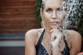 Shooting in the aquazone with falling water drops. A girl with blond hair in a black swimsuit under a cold shower in a recreation Royalty Free Stock Photo