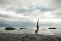 Woman doing a handstand on a rock at sunset on Bakovern Beach, Cape Town.