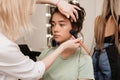 Shooting in a beauty salon. A master makeup artist applies blush, highlighter and a sculptor to the skin of a model& x27;s