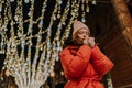 Shooting from below of frozen young woman in hat and winter jacket warming hands in cold winter night standing posing on Royalty Free Stock Photo