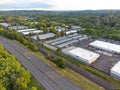 Shooting from a drone. Large highway, industrial buildings. Lots of greenery. In the background is a small green suburb with