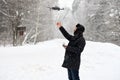Shooting from a drone in winter in a snowfall. A man with a drone on the road in the forest. The quadcopter sits on the man`s arm