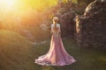 Shooting without a face, from the back. Wonderful princess with blond hair and a crown. is wearing an amazing light pink