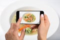 Shooting food on phone`s camera. Chicken soup with broccoli, carrots and celery in a white bowl on a white background. Royalty Free Stock Photo