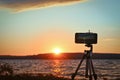 Shooting a time-lapse with a smartphone of a sunset over a lake. Shallow depth of field, smartphone focusing