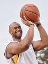 He shoots, he scores. a handsome young man playing basketball outside.