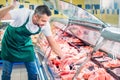 shop assistant in apron assorting fresh raw meat