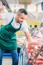 shop assistant in apron assorting fresh raw meat