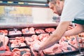 shop assistant in apron assorting fresh raw meat