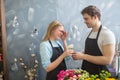 Shop assistant giving flower to his embarrased collegue