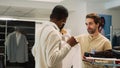 Shop assistant helping man to choose shirts from racks