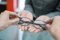 a shop assistant& x27;s hand gives a pair of glasses to the hand of a customer