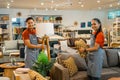 shop assistants in apron with their friend working to tidy up