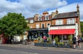 A shop and a bakery in Dulwich Village with people enjoying the summer sunshine