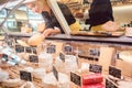 Shop clerk woman sorting cheese in the supermarket display Royalty Free Stock Photo