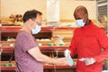 Shop employee at the entrance of the supermarket spraying disinfectant on customers hands