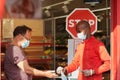 Shop employee at the entrance of the supermarket spraying disinfectant on customers hands