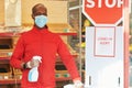 Shop employee at the entrance of the supermarket spraying disinfectant on customers hands