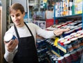 Shop employee posing near stand with wall paint