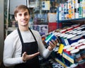 Shop employee posing near stand with wall paint